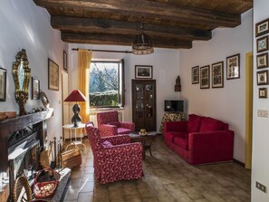 Cozy living room with a fireplace, comfortable sofa, and armchair, featuring a wooden cabinet and television.