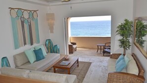 Een ruime woonkamer met uitzicht op de oceaan, een plafondventilator en een groot raam.
