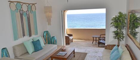 Een ruime woonkamer met uitzicht op de oceaan, een plafondventilator en een groot raam.