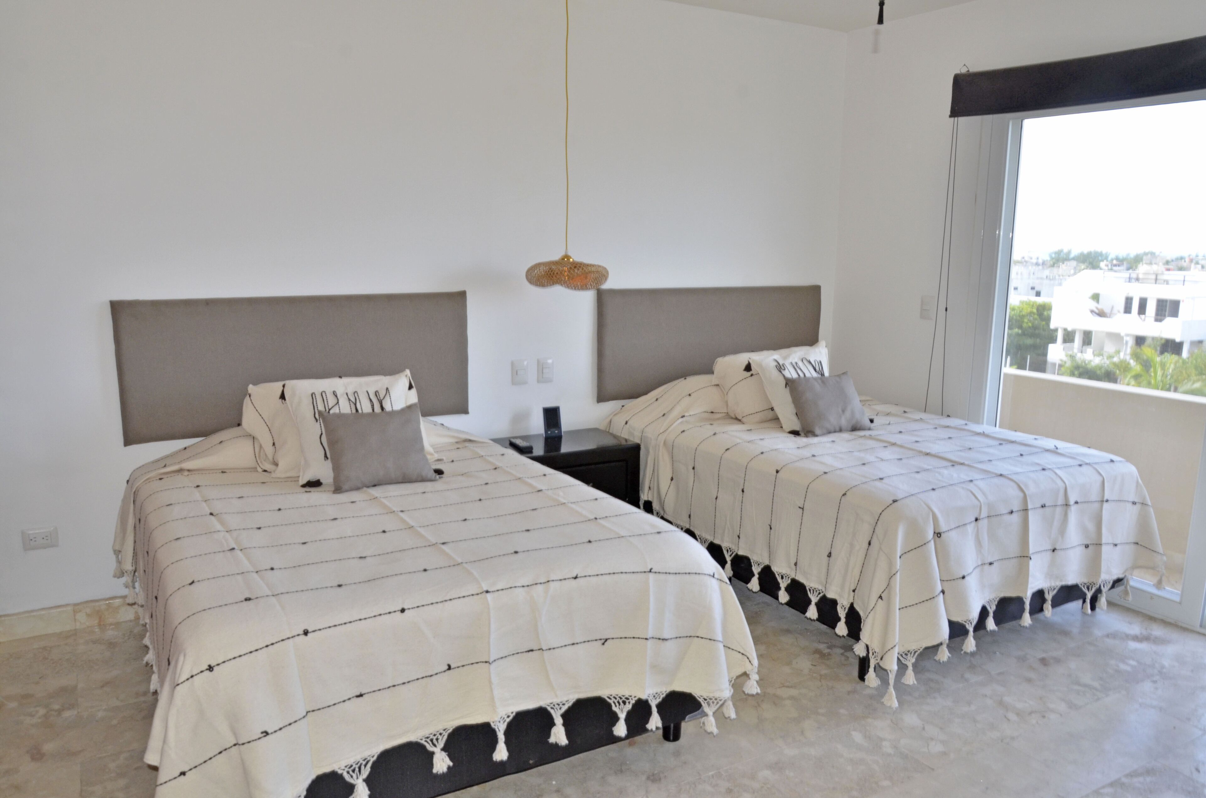 A room with two beds, each with a headboard and a bedside table.