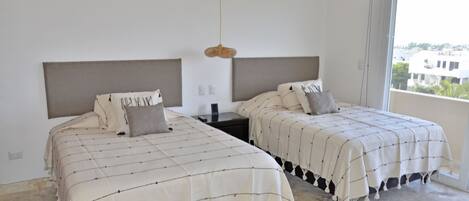 A room with two beds, each with a headboard and a bedside table.