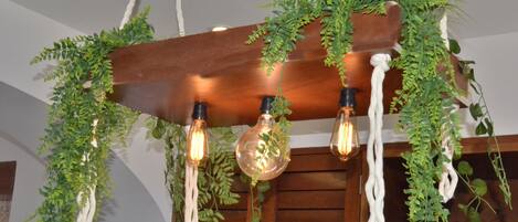 A wooden ceiling with three exposed light bulbs and hanging greenery.