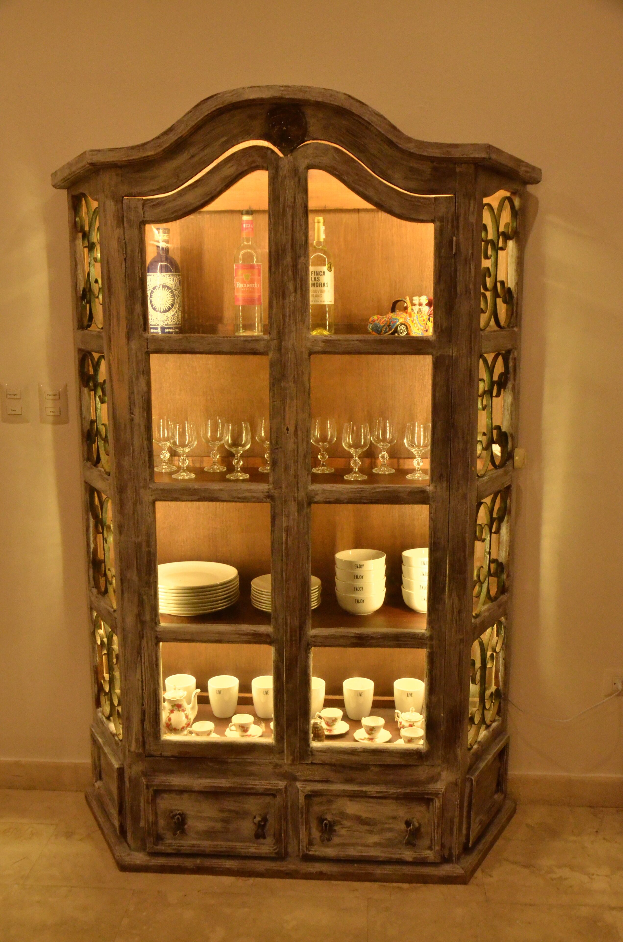 Un armario de madera con puertas de cristal, que contiene varios vasos y platos.