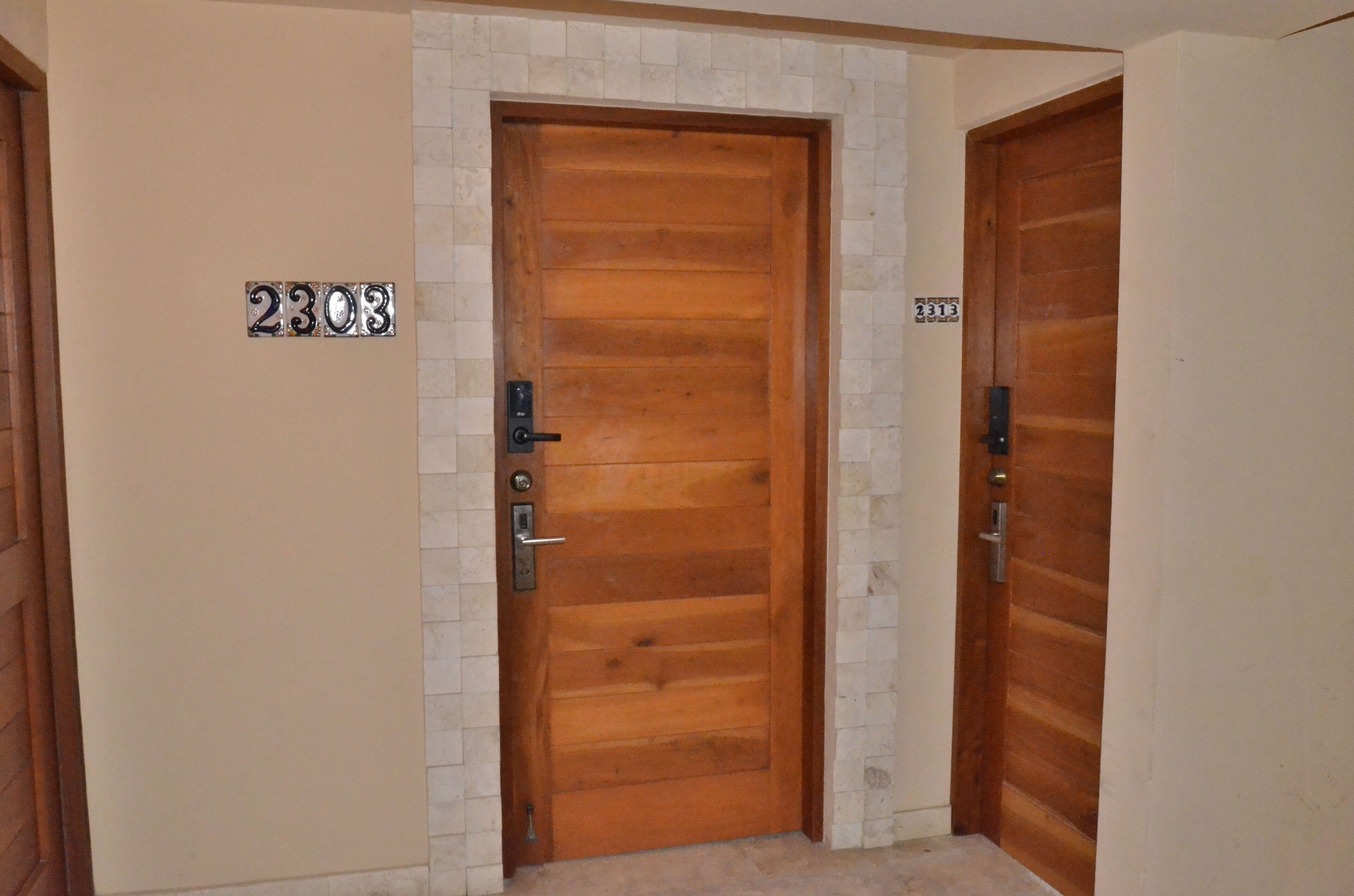 A wooden door with a metal handle and a numeric plaque reading '2303'.