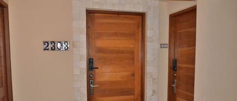 A wooden door with a metal handle and a numeric plaque reading '2303'.