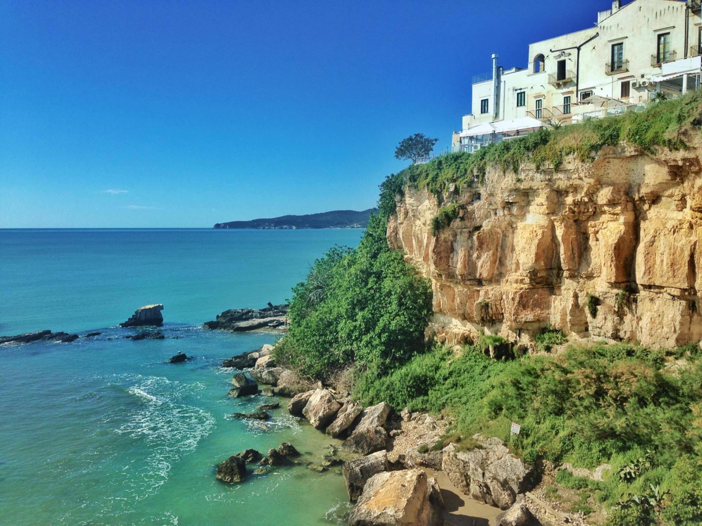Une falaise côtière surmontée d’un bâtiment, d’où l’on a une vue sur la mer.