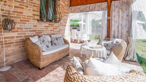 Ein gemütliches Zimmer mit Backsteinwand, Korbmöbeln und Blick auf den Garten.