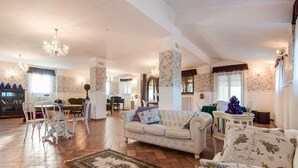 Ein geräumiges Wohnzimmer mit Klavier, einer Couch und einem Essbereich mit Stühlen.