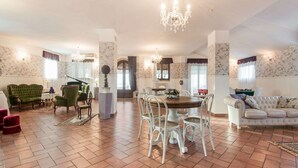 Ein geräumiger Wohnbereich mit Esstisch, Stühlen, einem Klavier und einer Couch.