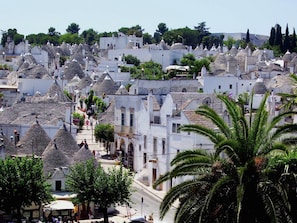 Une ville densément peuplée, avec des bâtiments blancs et des toits coniques, des rues étroites et des palmiers.