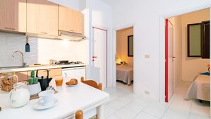 A compact kitchen with a dining area, a small bedroom, and a bathroom. - Belvilla by OYO Villini a Schiera (Altidona)