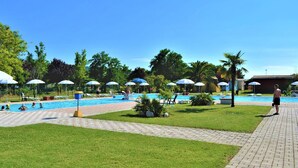 A pool area with multiple umbrellas, lounge chairs, and a clear blue sky. - Belvilla by OYO Villini a Schiera (Altidona)