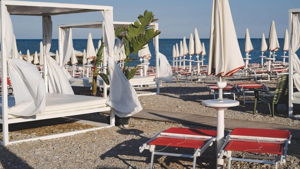 A beachside hotel with white cabanas, red lounge chairs, and umbrellas. - Belvilla by OYO Villini a Schiera (Altidona)