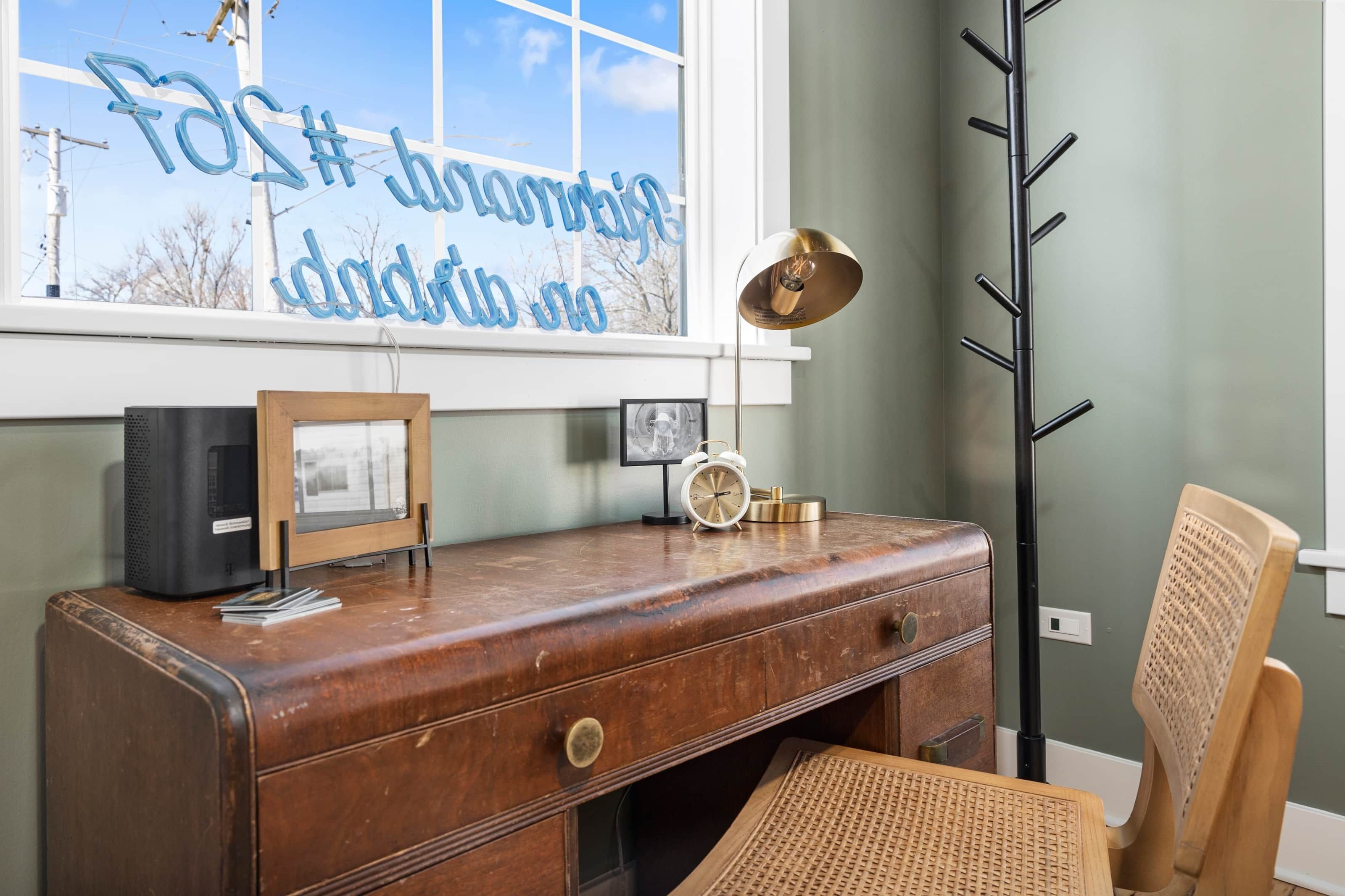 Un bureau en bois ancien, orné d’un cadre photo, d’une horloge et d’une lampe.