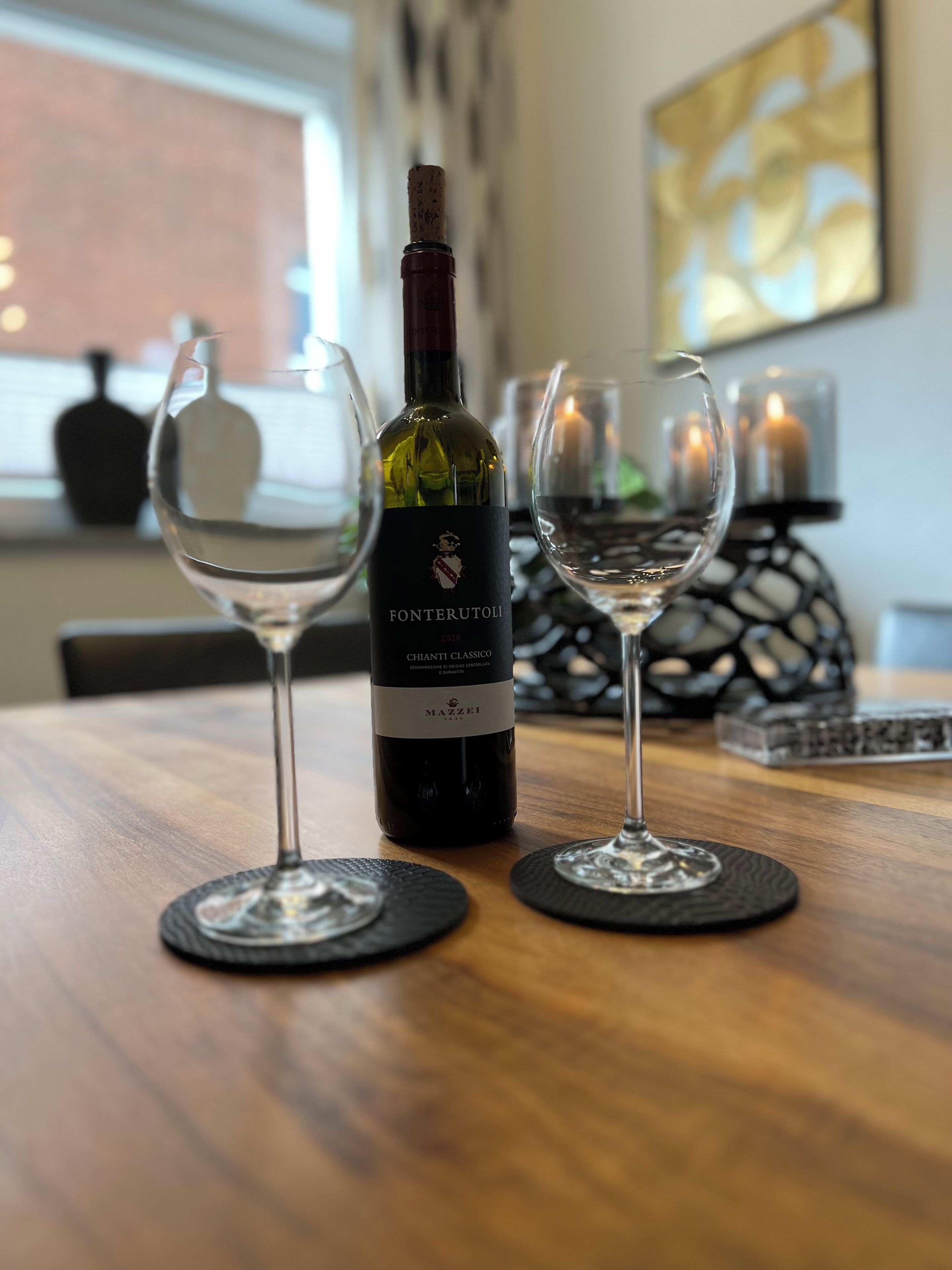 En flaska Chianti Classico-vin och två glas på ett träbord.