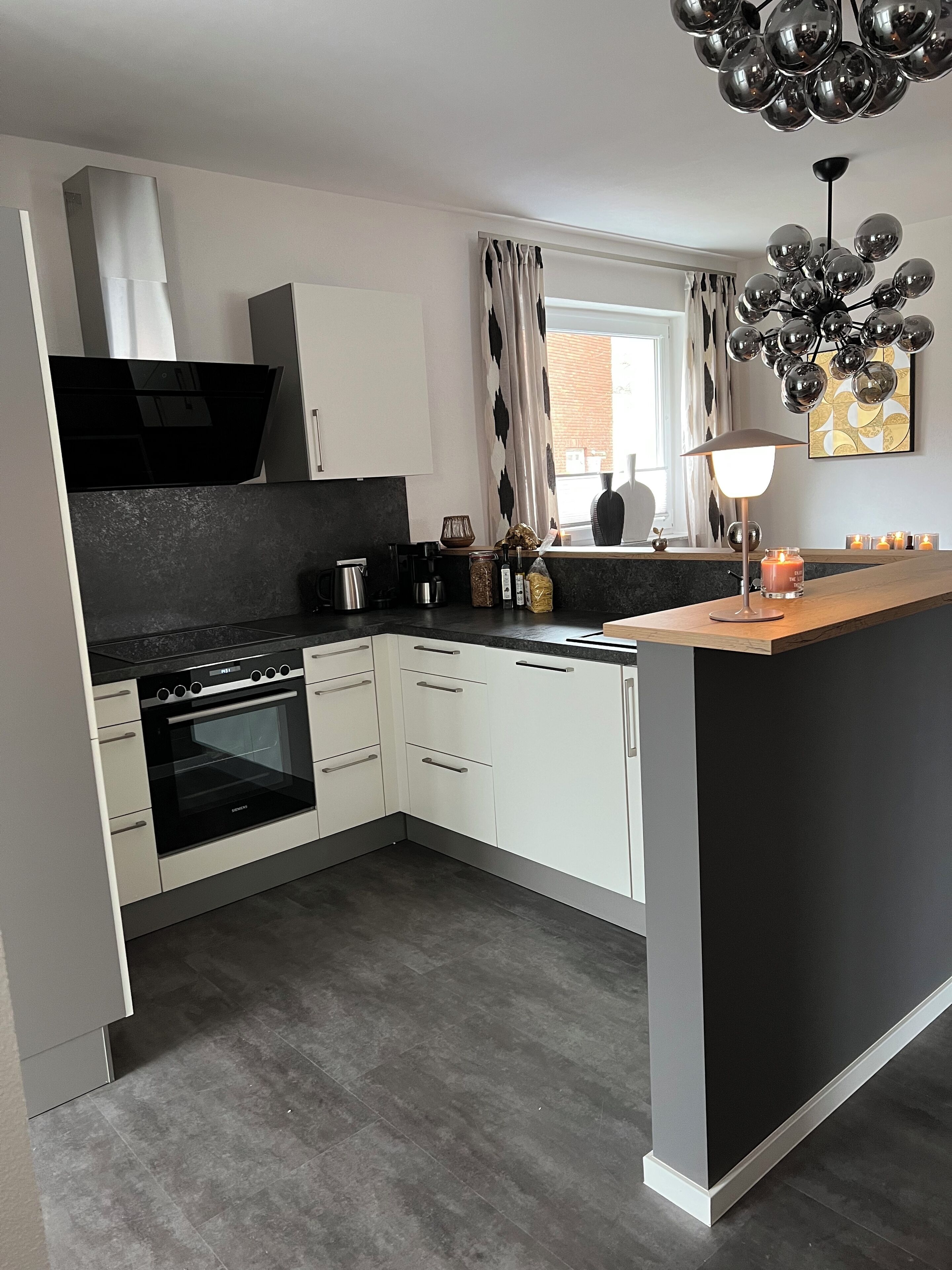A modern kitchen with white cabinets, a black stove, and a wooden island.