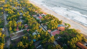 An aerial view of a coastal residential area with houses surrounded by palm trees, a beach, and the ocean. - Private Beach side Home - Playa San Diego (La Libertad)