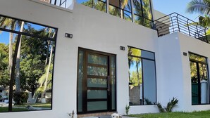 A modern two-story house with large windows, a balcony, and a well-maintained lawn. - Private Beach side Home - Playa San Diego (La Libertad)