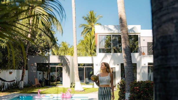 A modern building with a pool, surrounded by palm trees and greenery. - Private Beach side Home - Playa San Diego (La Libertad)