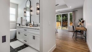 A modern bathroom with a freestanding bathtub, a large mirror, and a vanity with a sink.