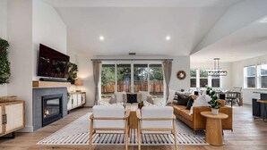 A spacious living room with a fireplace, a dining area, and a kitchen.