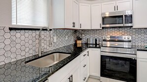 A kitchen with white cabinets, a stainless steel microwave, a toaster, and a Samsung oven. - Blue Horizon Retreat- Near Downtown McKinney  (McKinney)