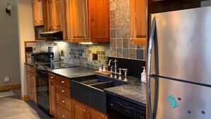 A modern kitchen with wooden cabinets, a stainless steel refrigerator, and a tiled backsplash. - Private Lakefront with Dock! (MONGAUP VALLEY)