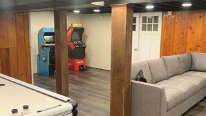 A pool table, a sofa, a red arcade machine, and a door in a room with wooden walls and a ceiling. - Private Lakefront with Dock! (MONGAUP VALLEY)