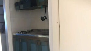 A kitchen with a gas stove, cabinets, and hanging utensils. - Belvilla by OYO Sant Irene (Briatico)
