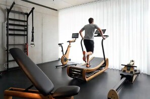 A gym with exercise equipment, a bench, and a wall-mounted rack.