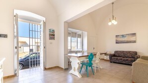 A spacious living area with a dining table, chairs, a sofa, and a kitchen area. - Apartment Marina di Mancaversa by Ionian Sea (Taviano)
