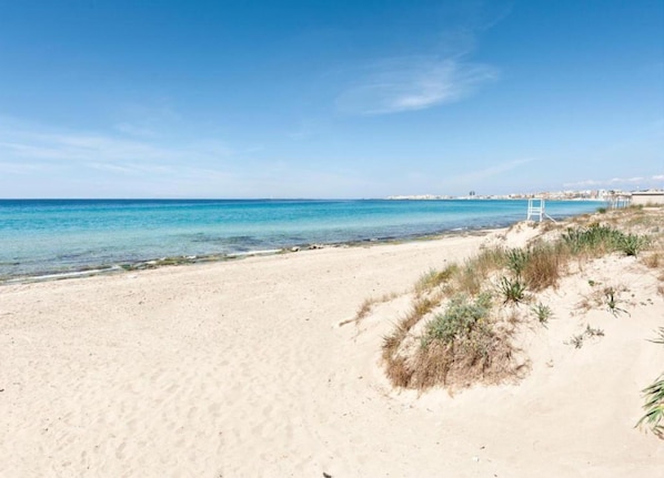Enjoy a serene beach experience with gentle waves and a lifeguard tower nearby.