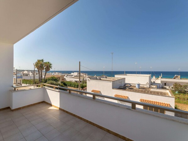 A balcony with a clear view of the sea and surrounding buildings.