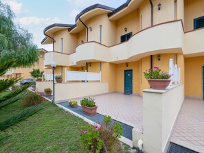 A multi-story building with a curved facade, outdoor potted plants, and a gated entrance. - Belvilla by OYO Conca Degli Dei con Patio (Capaccio-Paestum)