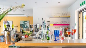 Zona de bar con varias botellas y vasos, un mostrador de madera y un letrero de salida verde.