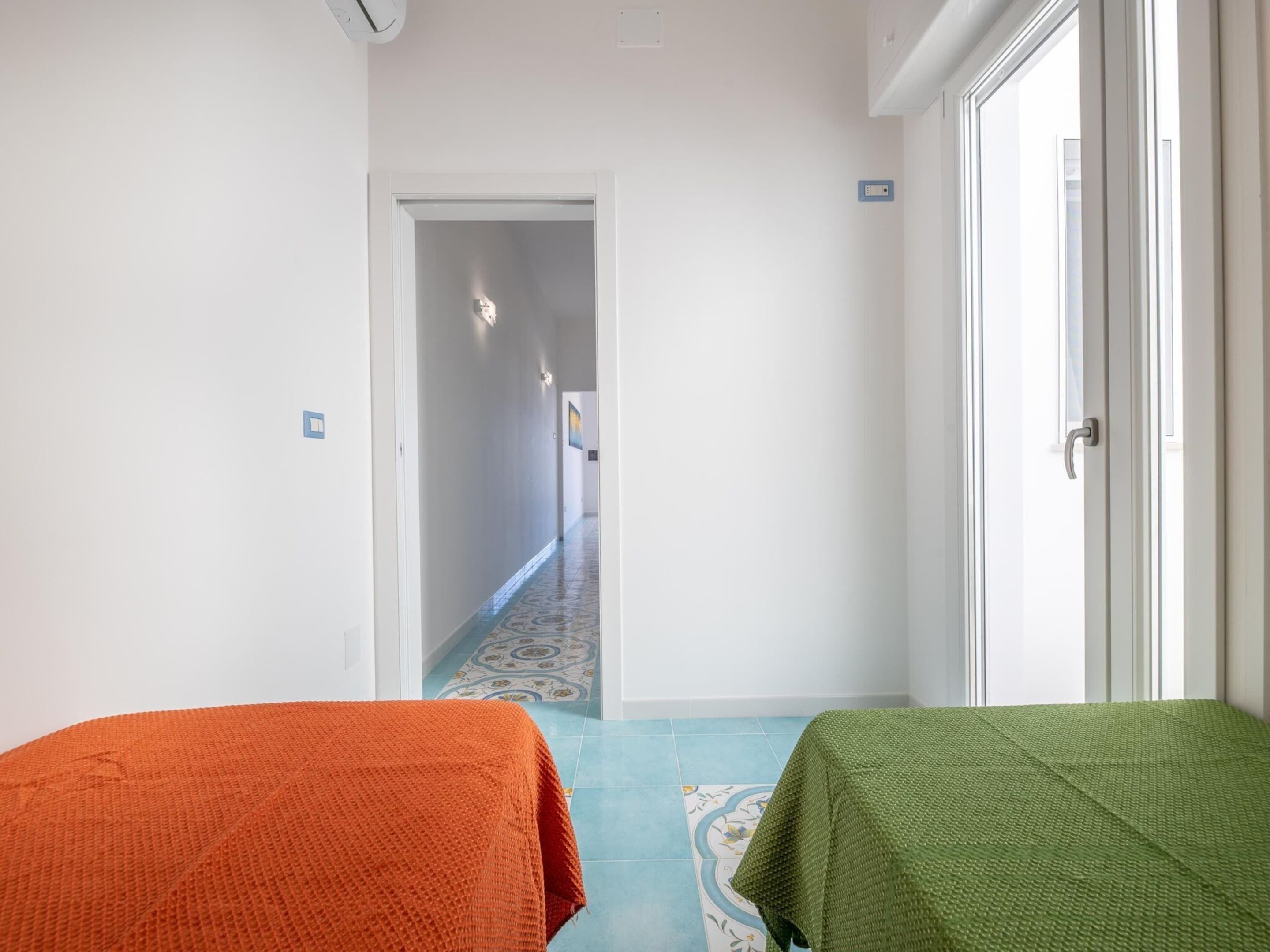 A hallway with a patterned floor leading to a room with a door.