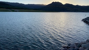Un lac paisible, avec des montagnes en arrière-plan et un ciel dégagé.