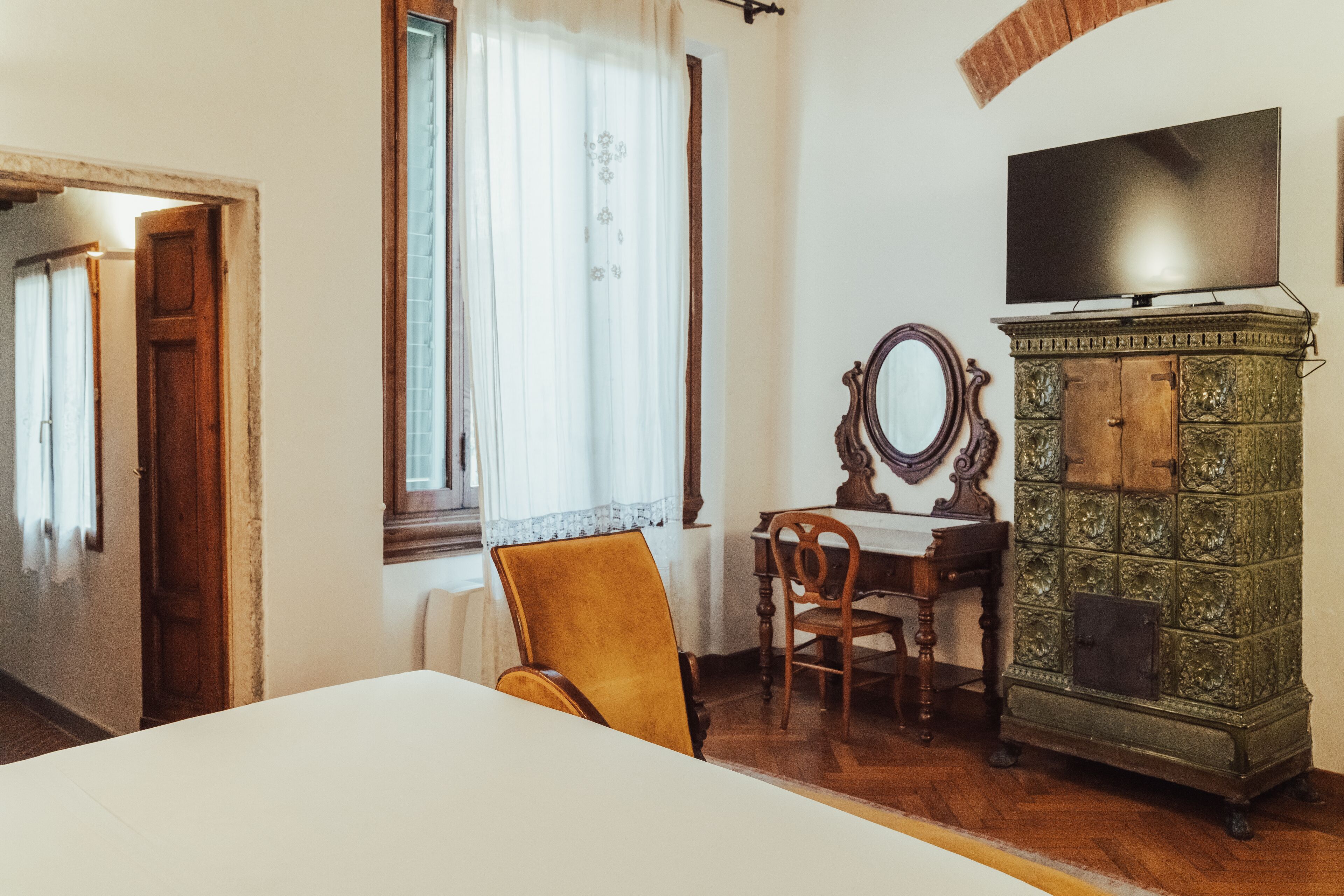 Ein Zimmer mit einem Holztisch, einem Stuhl, einem Fernseher auf einem Schrank und einem Spiegel an der Wand.