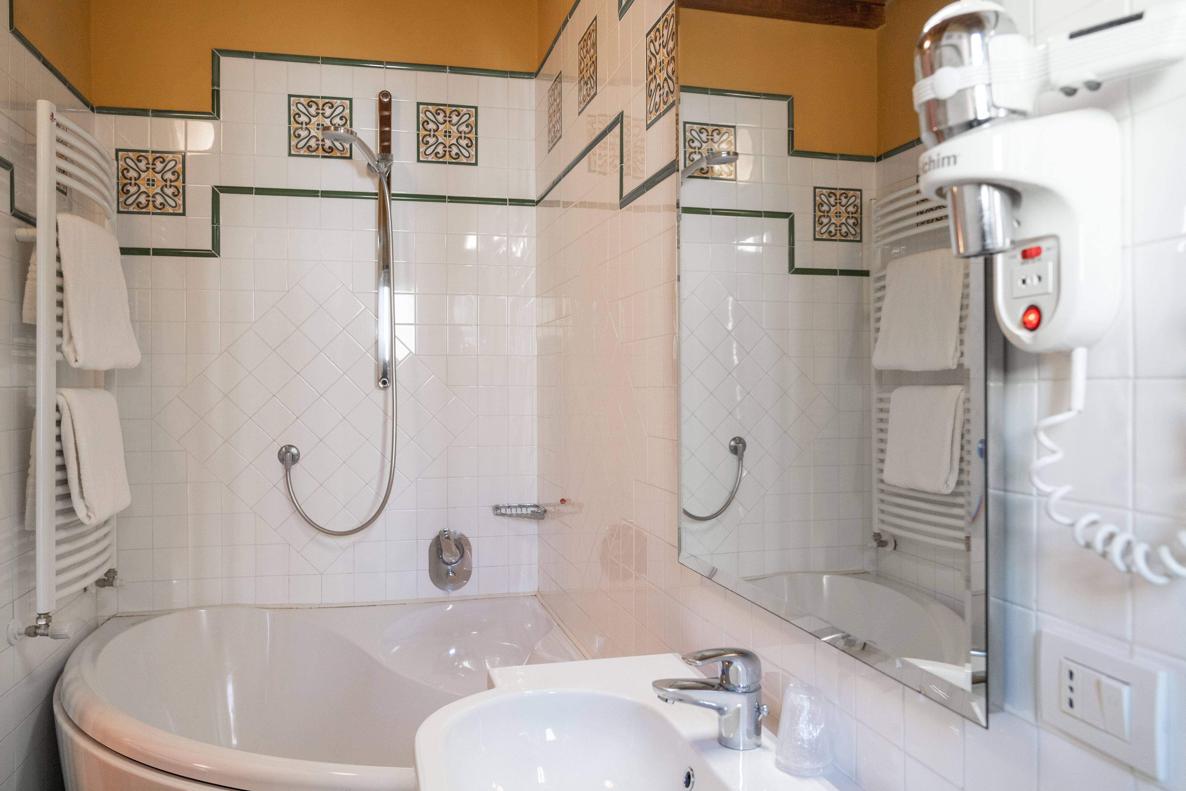 A bathroom with a bathtub, a sink, a mirror, and a towel rack.