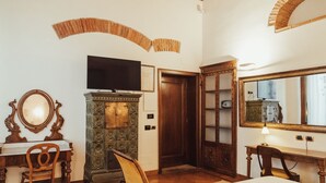 A room with a wooden desk, a television on a stand, a mirror, and a cabinet. - Il Guelfo Bianco (Florence)