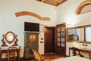 Quarto com escrivaninha de madeira, televisão em móvel, espelho e armário.