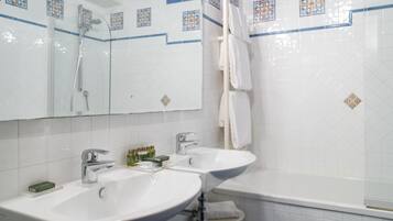 Een badkamer met twee wasbakken, een douche en een bad.