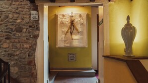 A staircase leading to a room with a stone wall, a framed artwork, and a vase on a shelf. - Il Guelfo Bianco (Florence)
