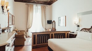 A hotel room with a large bed, a wooden dresser, a desk, and a television on the wall. - Il Guelfo Bianco (Florence)