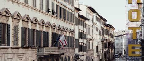 A historic building with multiple stories, large windows, and a prominent flag.