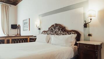A neatly made bed with white linens, a wooden headboard with a floral pattern, and two wall-mounted lamps.
