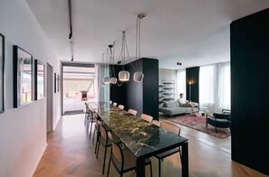 Un espace de salle à manger moderne avec une longue table, des chaises et des luminaires suspendus.
