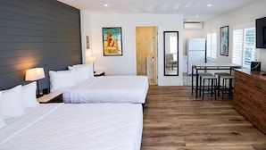 Une chambre d’hôtel avec deux lits, un plancher en bois, un bureau avec des chaises et un téléviseur fixé au mur.