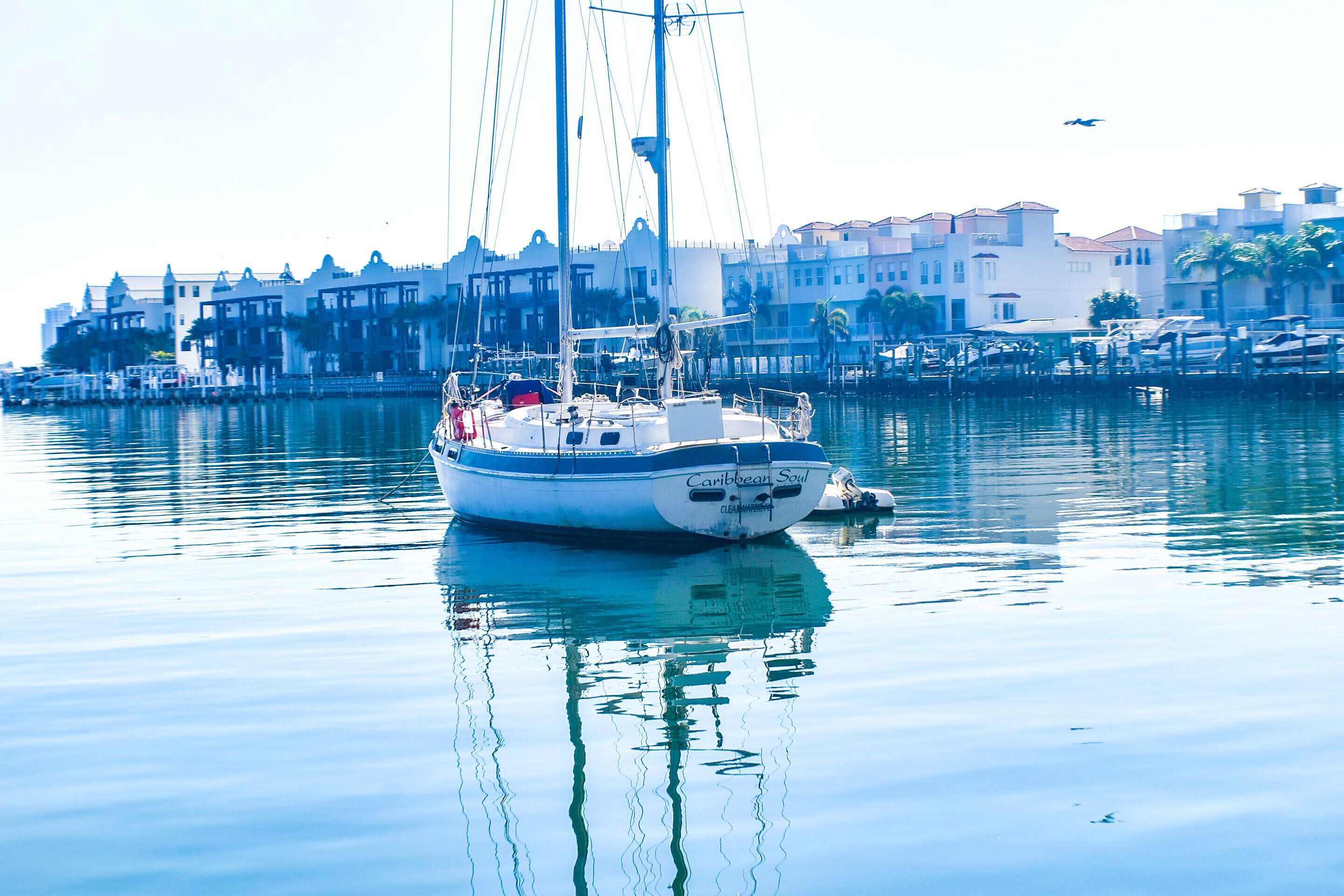 A sailboat docked at a marina with buildings in the background.