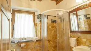 A bathroom with a shower, a sink, and a window with a curtain.